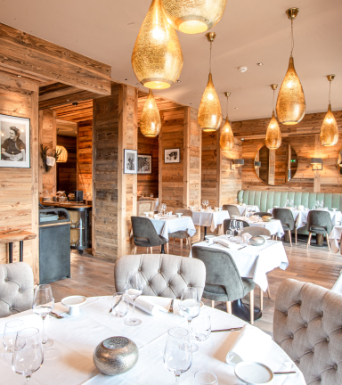 Restaurant avec mur en bois, chaises en tissu et table ronde.